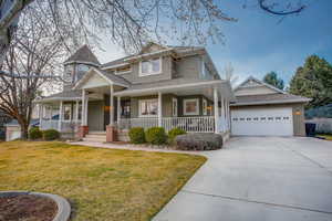Victorian home with covered porch, a front lawn, a shingled roof, driveway, and an attached garage