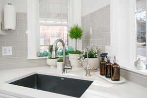 Kitchen view of backsplash, light stone counters, and water heater