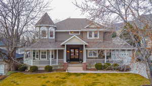Victorian home featuring a porch, roof with shingles, a front lawn, and french doors