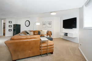 Living area with baseboards and light carpet