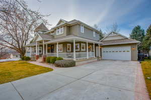 View of front of home with a porch, a front yard, roof with shingles, concrete driveway, and an attached garage