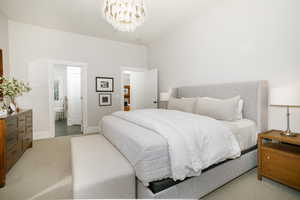 Bedroom featuring carpet, hanging lights, and ensuite bathroom