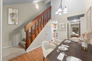 Dining area featuring light wood-style floors, a chandelier, and vaulted ceiling