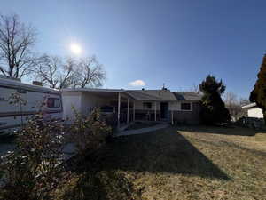 Rear view of house with a lawn, a carport, a patio, and brick siding