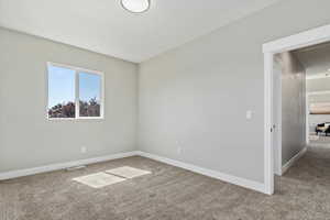 Carpeted spare room featuring baseboards
