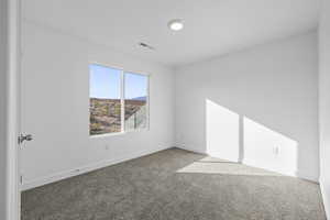 Carpeted spare room featuring baseboards