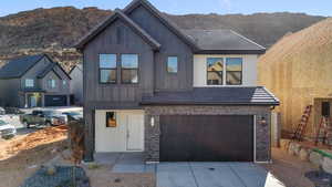 View of front of property with board and batten siding, a garage, a mountain view, driveway, and brick siding