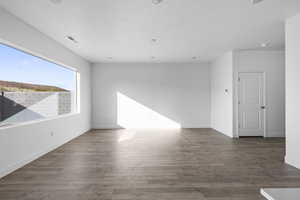 Spare room featuring dark wood finished floors and baseboards