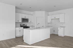 Kitchen with white cabinets, a center island with sink, and stainless steel appliances