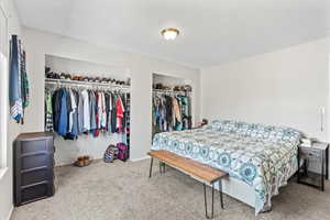Bedroom with light colored carpet and multiple closets
