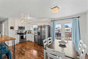 Kitchen with stainless steel appliances, white cabinets, light countertops, a textured ceiling, and dark wood finished floors