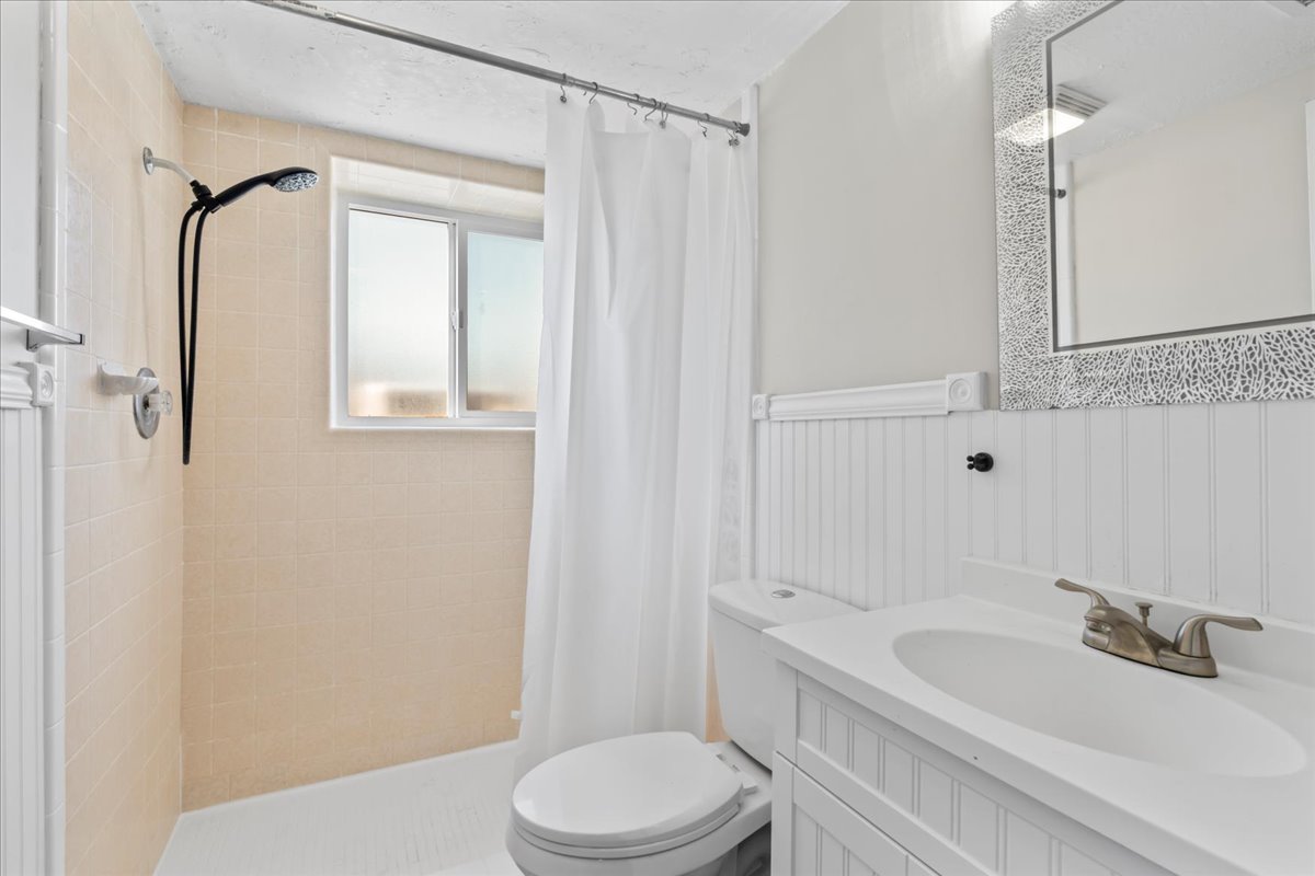 Bathroom featuring vanity, a shower stall, and wainscoting