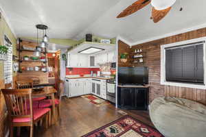 Kitchen featuring wood walls, white cabinetry, hanging light fixtures, dark wood-style floors, and lofted ceiling