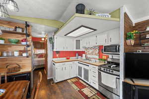 Kitchen featuring white cabinetry, stainless steel appliances, dark wood-style floors, and a textured ceiling