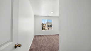 Empty room featuring dark colored carpet and a textured ceiling
