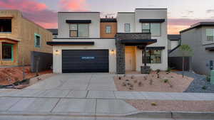 Contemporary house with stone siding, stucco siding, driveway, and a garage