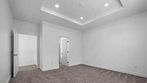 Unfurnished bedroom featuring a tray ceiling, carpet flooring, and recessed lighting