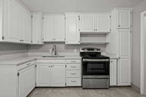 Kitchen featuring electric stove and white cabinetry