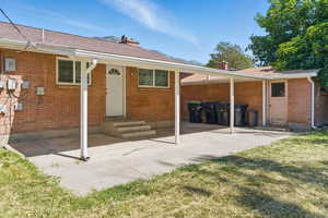 Rear view of house with a patio, a chimney, and brick siding