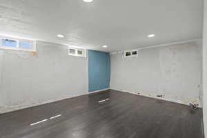 Basement with dark wood finished floors, a textured ceiling, and recessed lighting