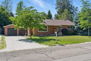 Ranch-style house with an outbuilding, a garage, a front lawn, and brick siding