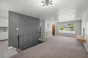 Unfurnished living room featuring light carpet, a fireplace, and a textured ceiling