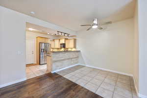 Kitchen featuring light tile patterned flooring, ceiling fan, light wood finish cabinetry, stainless steel appliances, and rail lighting