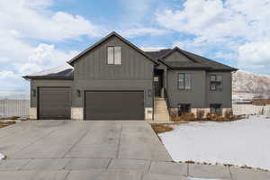 View of front of house with a mountain view, board and batten Hardie siding, a garage, and driveway