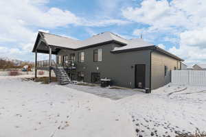 Back view of home with covered deck and walkout patio, black-framed windows, and Hardie siding