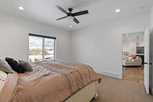 Primary bedroom with light carpet, ceiling fan, and recessed lighting