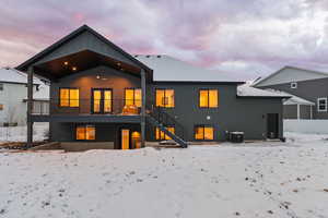 Back view of home with covered deck and walkout patio, black-framed windows, and Hardie siding