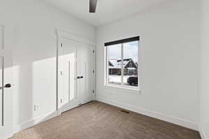 Main floor spare bedroom with carpeted floors, light paint, ceiling fan and natural light