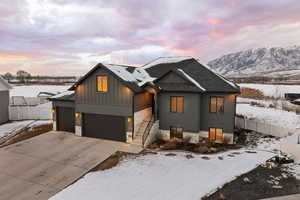 View of front of house with a mountain view, board and batten Hardie siding, a garage, and driveway featuring mountain backdrop