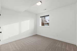 Basement spare bedroom featuring carpet floors, light paint, daylight window and ceiling fan