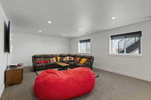 Basement living room featuring carpet and LVP floors, recessed lighting, garage entrance, and daylight windows