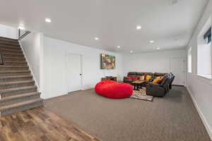 Basement living room featuring carpet and LVP floors, recessed lighting, garage entrance, and daylight windows