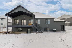 Back view of home with covered deck and walkout patio, black-framed windows, and Hardie siding
