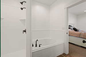 Ensuite bathroom featuring a soaker tub, a walk in shower, and dark LVP flooring