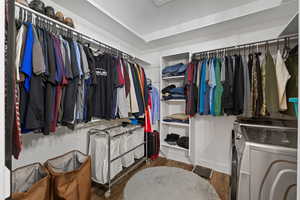Primary walk in closet with LVP flooring and ensuite washer/dryer pair