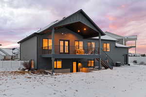 Back view of home with covered deck and walkout patio, black-framed windows, and Hardie siding