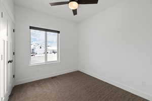 Main floor spare bedroom with carpeted floors, light paint, ceiling fan and natural light