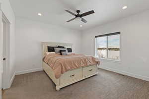Primary bedroom with light carpet, ceiling fan, and recessed lighting