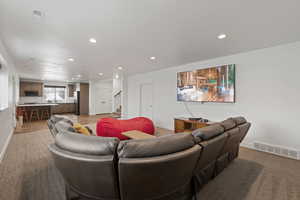 Open concept basement space featuring carpet and LVP floors, recessed lighting, living room and full kitchen