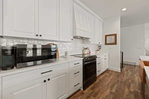 Kitchen with pendant lighting, black stainless steel appliances, a large island with sink, and tasteful backsplash