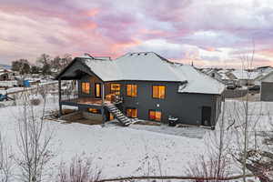 Snow covered property with a covered deck and patio area
