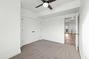 Basement spare bedroom featuring carpet floors, light paint, daylight window and ceiling fan