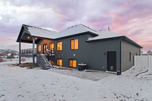 Back view of home with covered deck and walkout patio, black-framed windows, and Hardie siding
