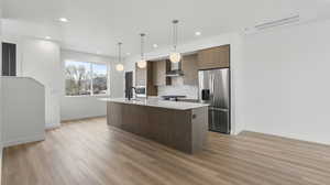 Photos are of a completed unit - Kitchen with stainless steel appliances, hanging light fixtures, a center island with sink, light stone counters, and modern cabinets