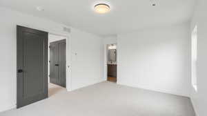 Photos are of a completed unit - Unfurnished bedroom with light carpet and connected bathroom