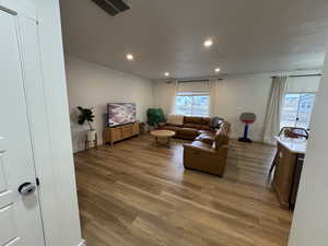 Living room with light wood-style flooring, recessed lighting, and a textured ceiling
